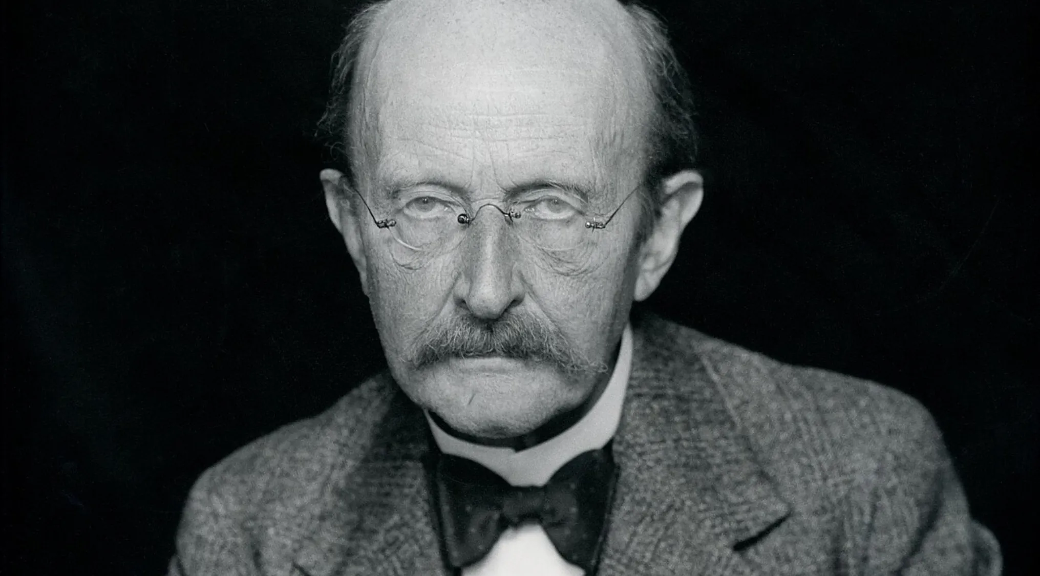 A black and white portrait of Max Planck, a theoretical physicist, wearing a suit and bow tie.