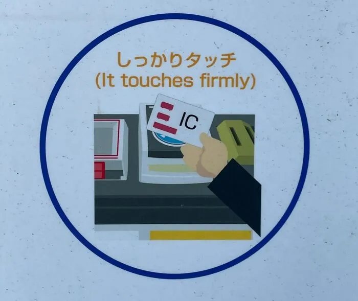 A circular sign in Japan with an illustration of a hand touching an IC card, text reads (It touches firmly), a hilarious example of getting lost in translation.
