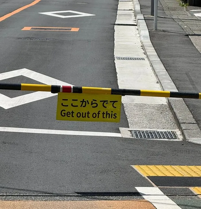 A yellow sign with the phrase Get out of this as an example of getting lost in translation in Japan.