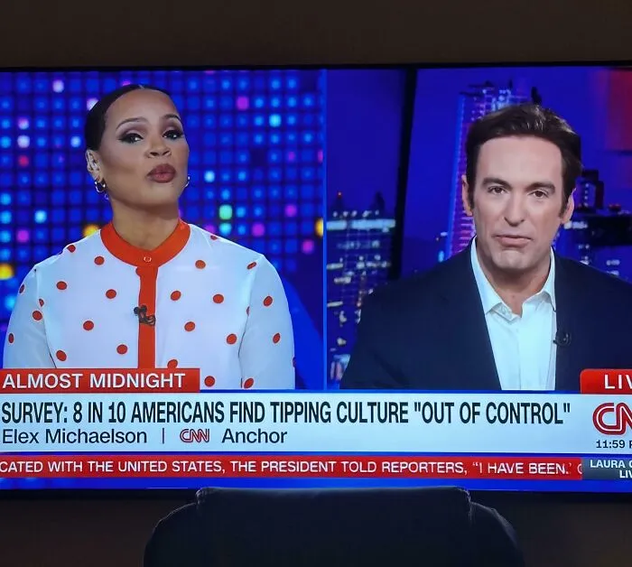 A TV screen showing a CNN news segment with anchors, displaying a headline about Americans finding tipping culture out of control.