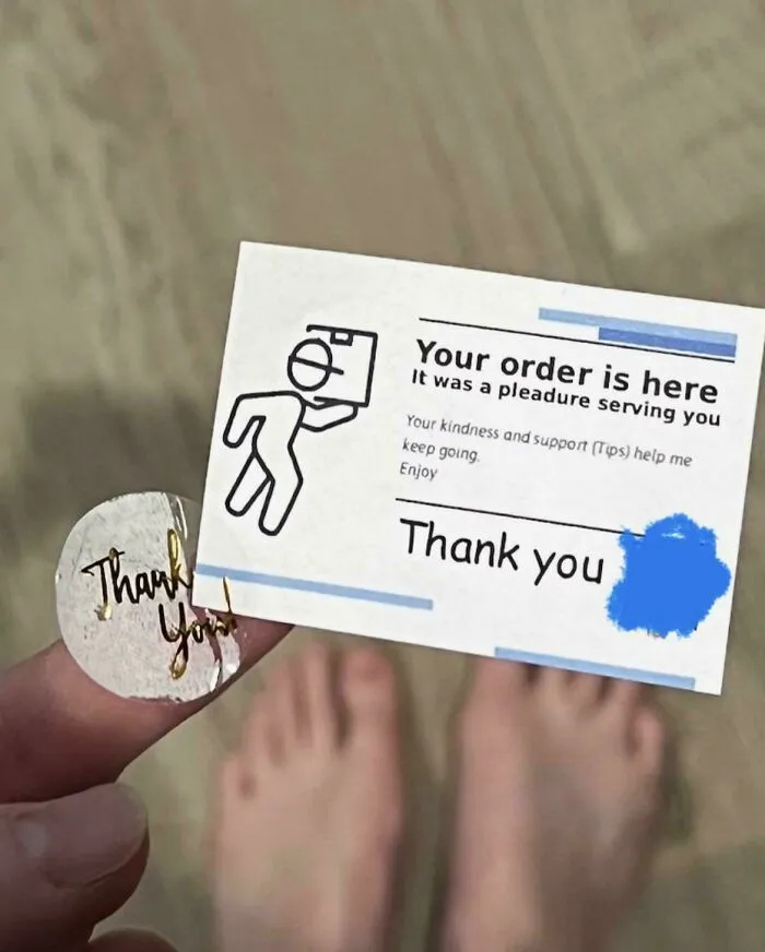 A thank you card and sticker on the floor near feet, implying the need for tips in tipping culture.