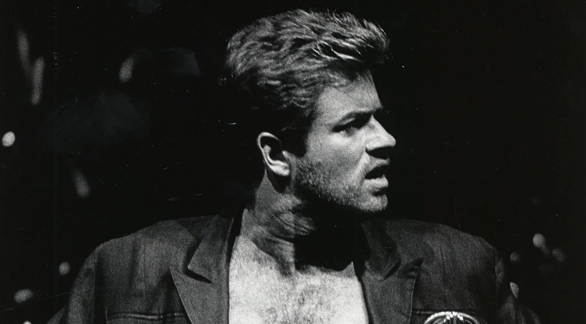 Black and white image of George Michael, with a serious expression, looking into the distance, launching into solo stardom.
