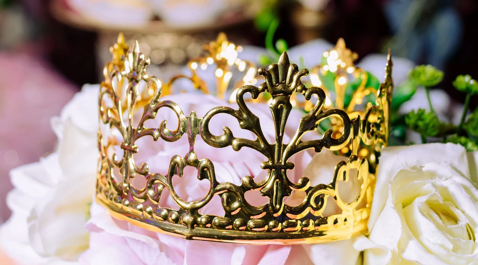 Golden crown, symbolizing the 'Queen of Rock 'n' Roll', rests on a bed of pink and white roses.