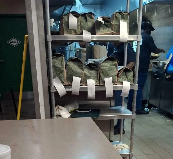 Restaurant kitchen with takeout bags, highlighting the busy environment where tipping culture impacts service workers.