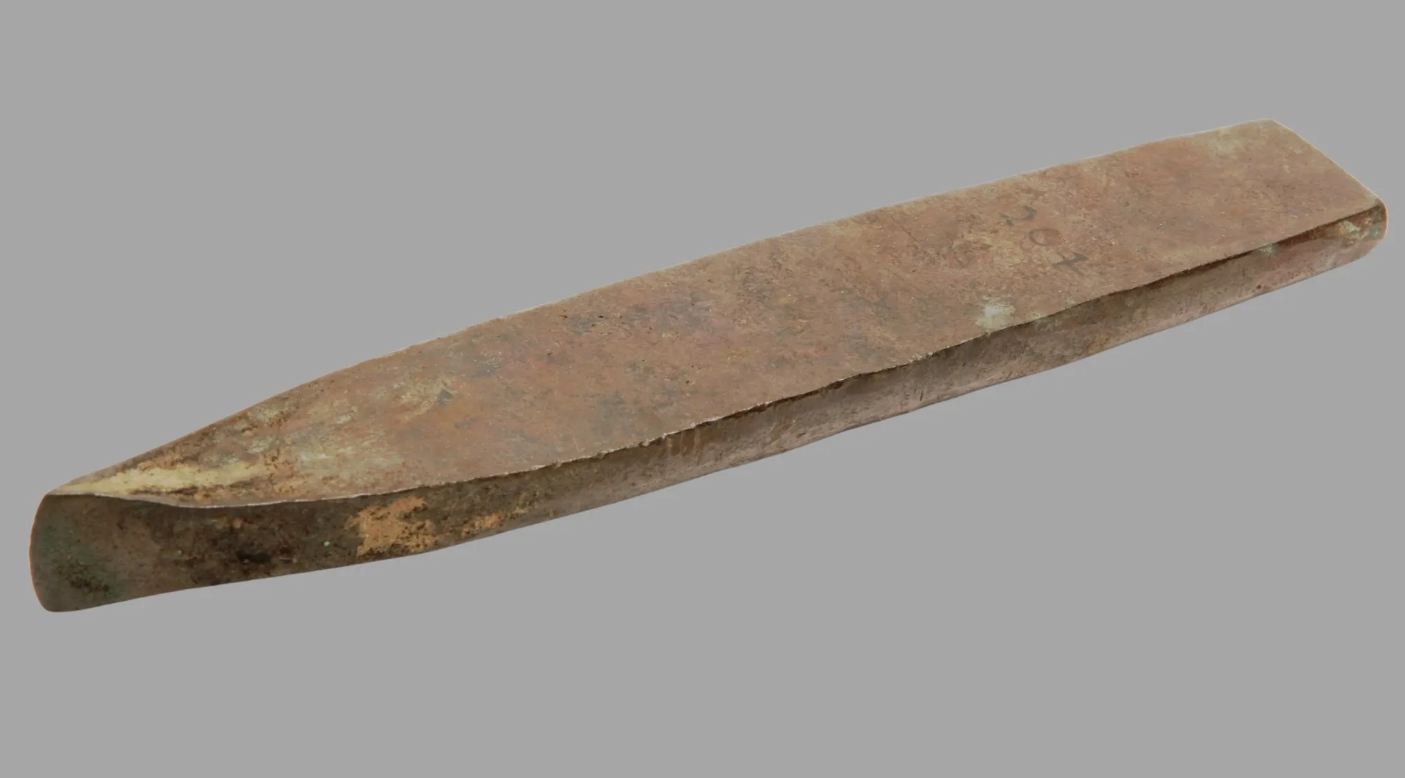 An ancient copper chisel, weathered with age and light green patina, displayed on a grey background.
