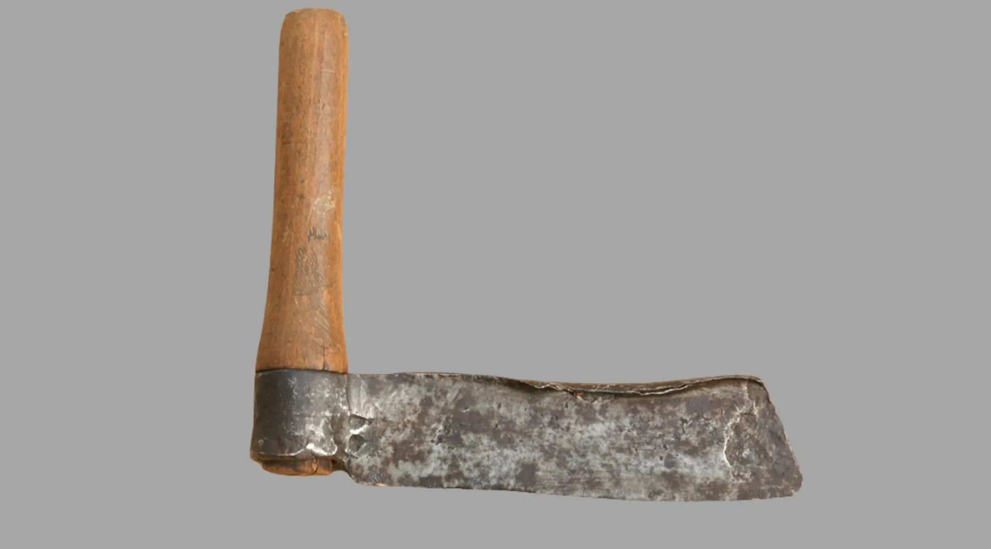 A close-up of an ancient tool, featuring a rustic wooden handle and a weathered, flat metal blade.