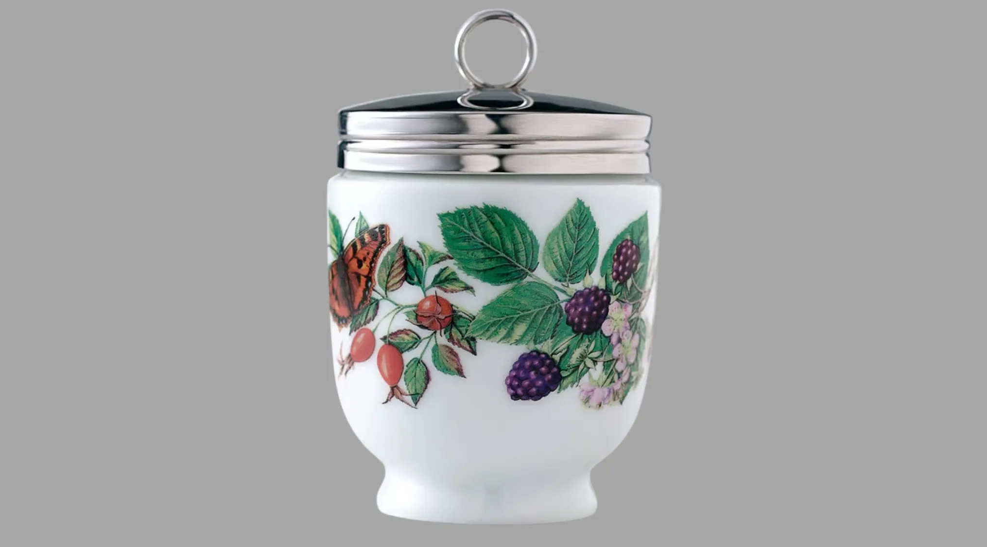 A decorative white porcelain egg cup with a metal lid and ring handle. Features a detailed illustration of a butterfly, berries, and leaves. Is this an ancient tool?
