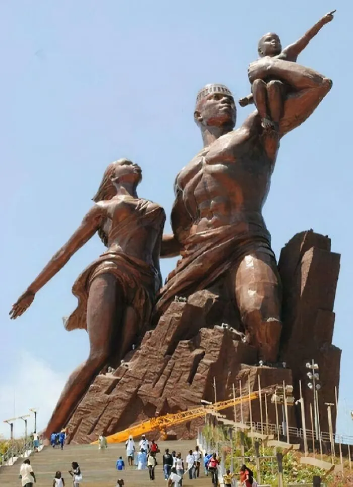 An eerie, extremely large monument of a family, emphasizing the grand scale of the statue against a clear sky.