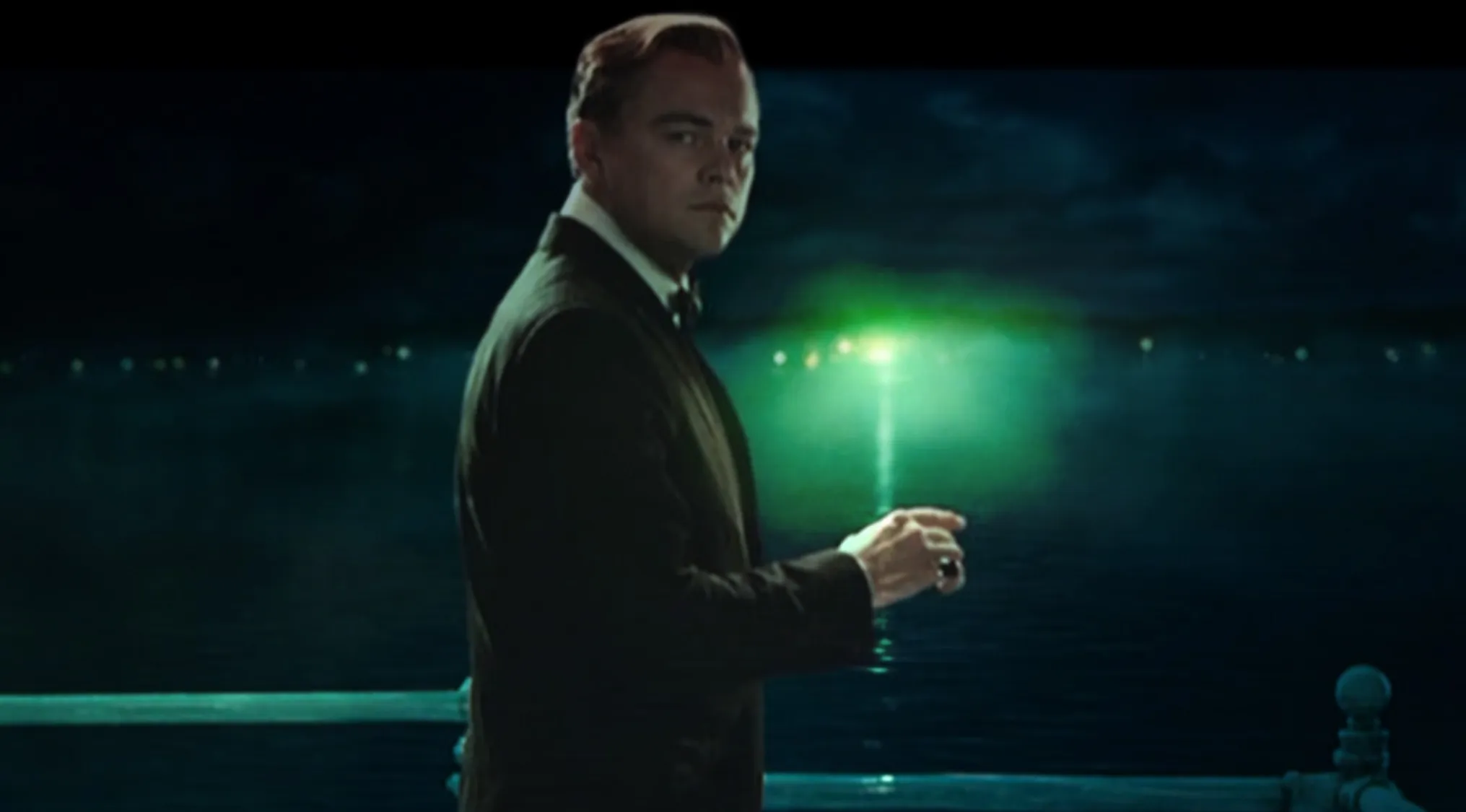 A man looking at a green light in the distance, representing the green light in The Great Gatsby, English Literature.