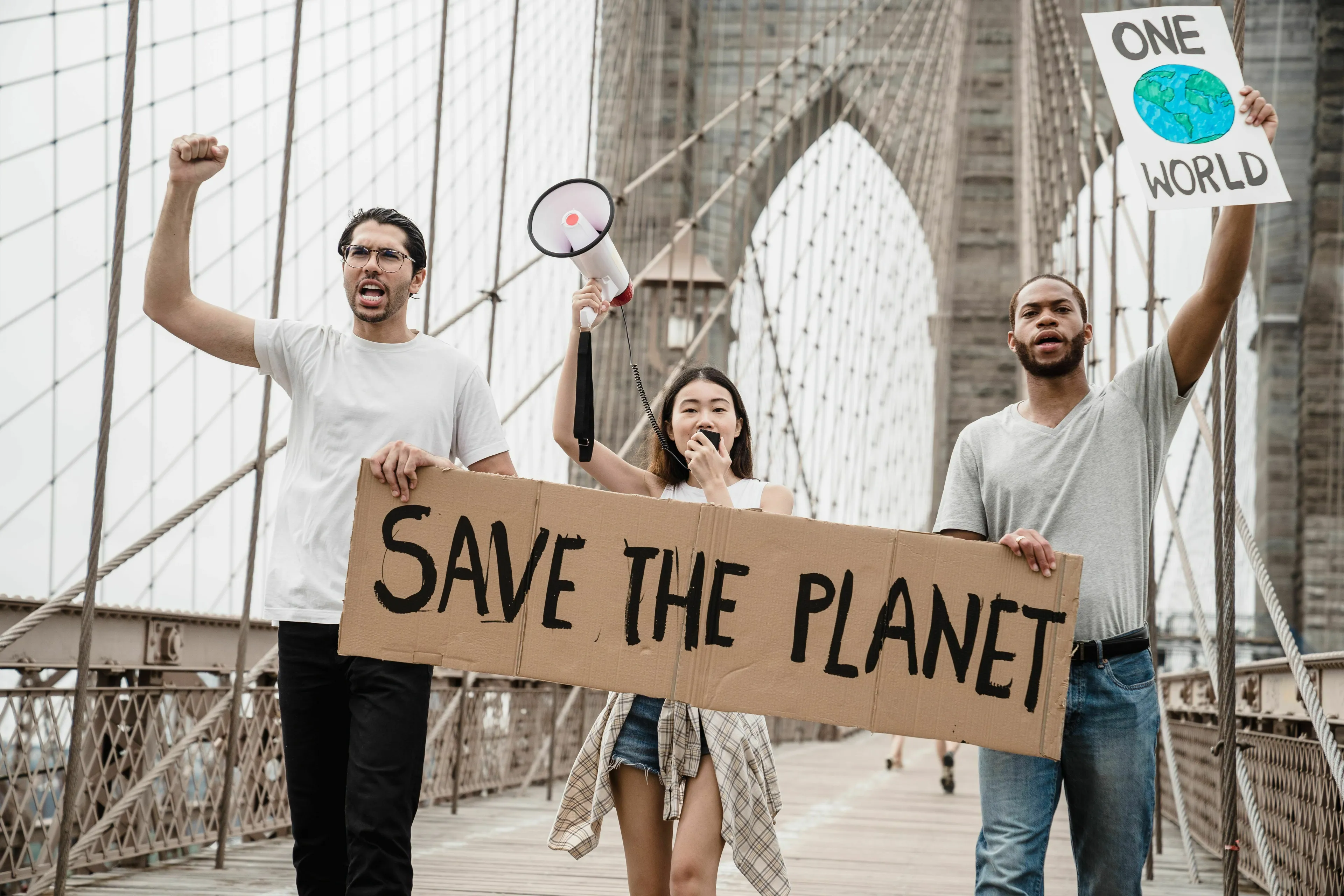 Environmental activists protesting on a bridge with signs and a megaphone, addressing rhetorical fallacy.