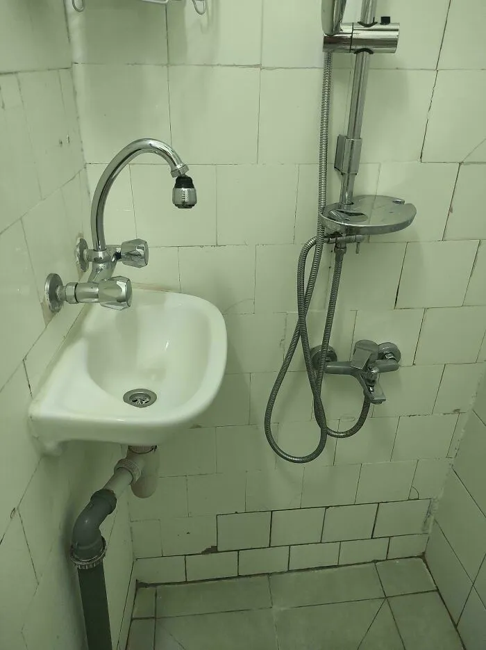 A photo showing an Airbnb bathroom blunder with a small sink next to a shower, highlighting poor design.