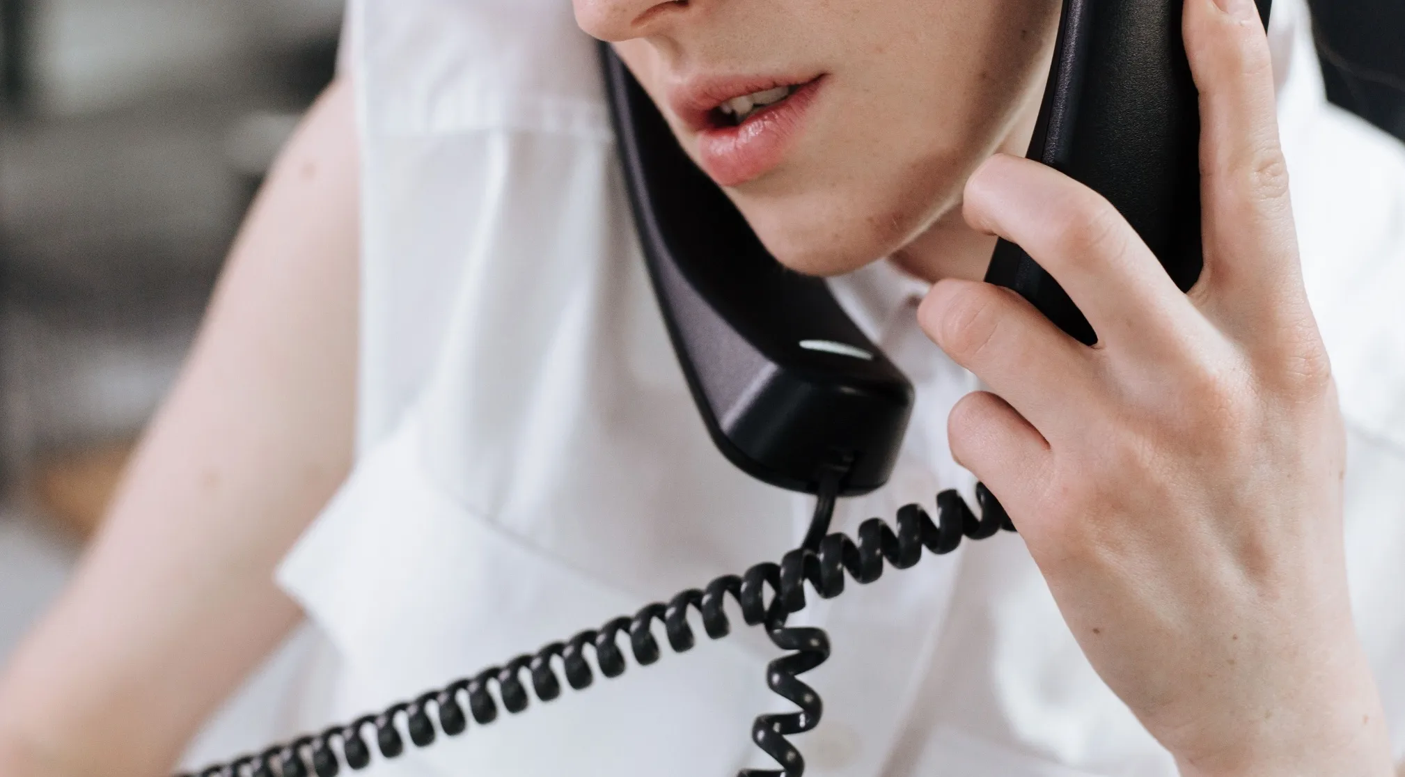 A person's face close up, wearing a white shirt and holding a phone to their ear. Double-meaning words.