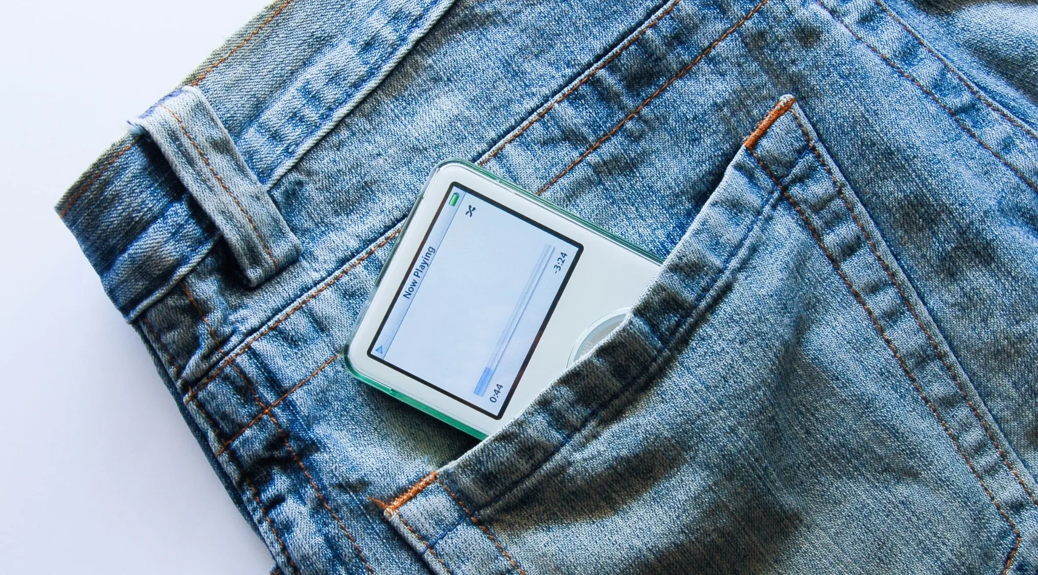 An iPod, a pocket-sized digital media player from Apple, in a jeans pocket, symbolizing 2000s pop culture.