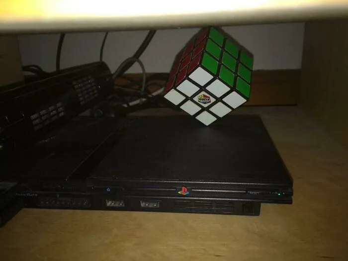 Wild and unhinged way to fix a tilted PlayStation 2 console with a Rubiks Cube to level it.