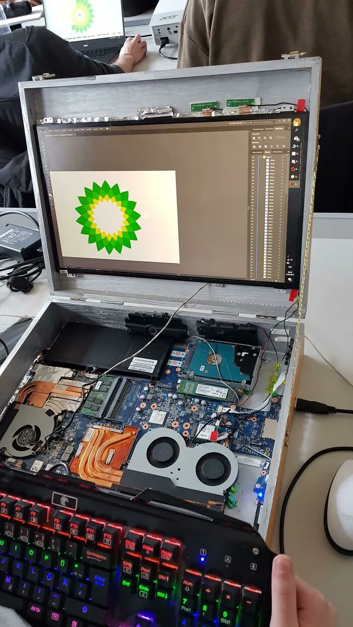 An open laptop with internal components exposed, displaying a BP logo, an unhinged way to fix or build.