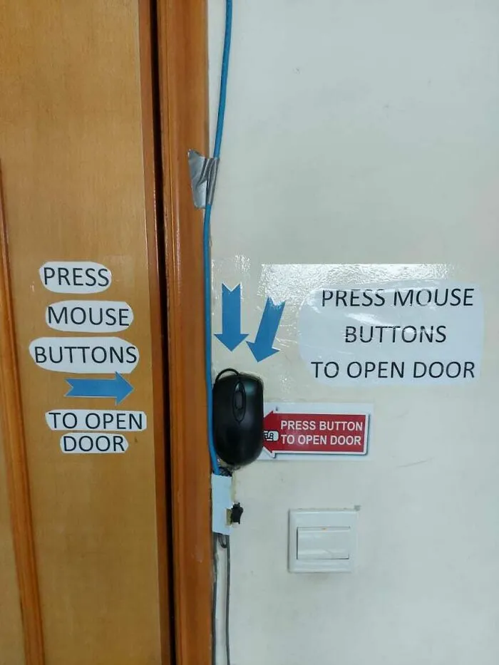 A computer mouse is taped to a wall, serving as a door opener, a wild way to fix something.