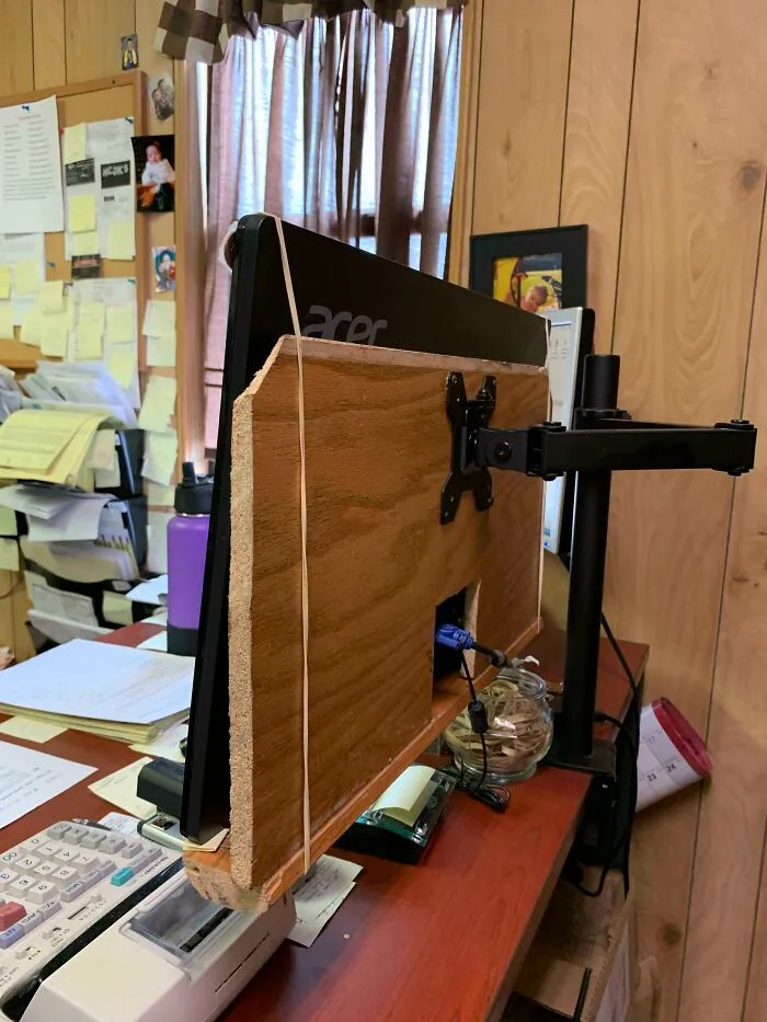 Wild and unhinged way to fix a monitor mount using wooden boards and rubber bands.