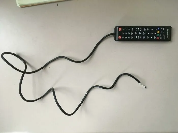 A Samsung remote control is attached to a long, winding cable, an unhinged way to fix something.