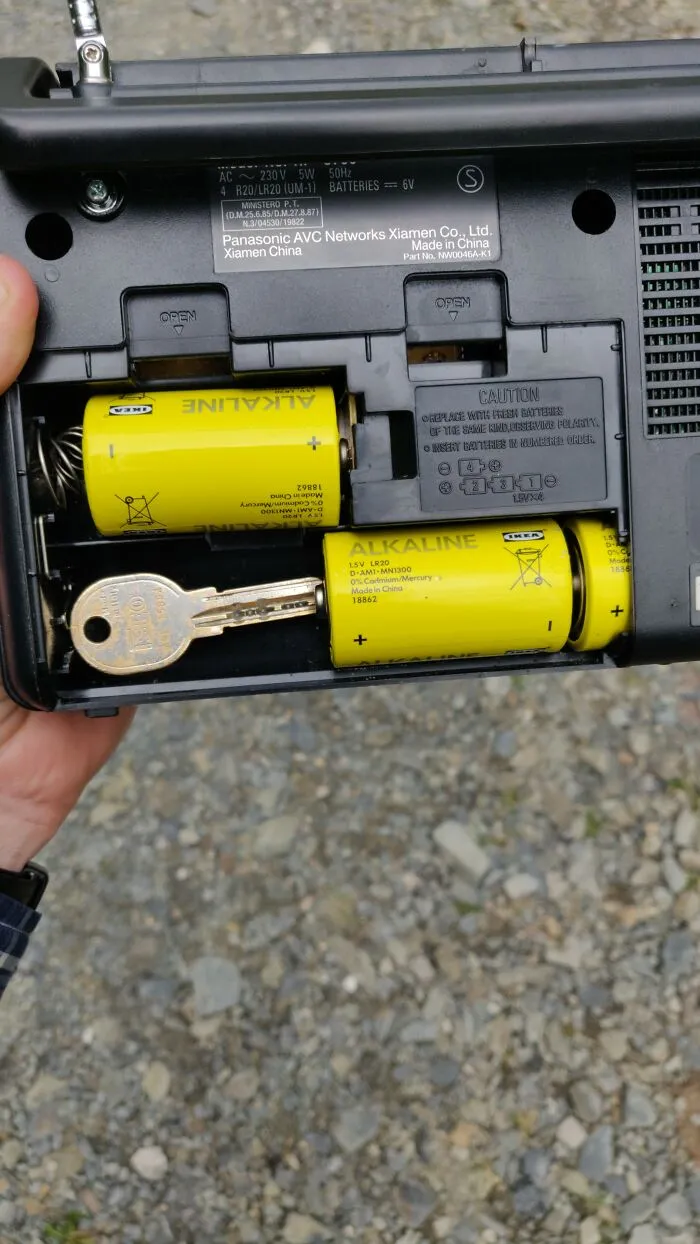 Wild and unhinged fix: a house key used as a spacer in a radio battery compartment.