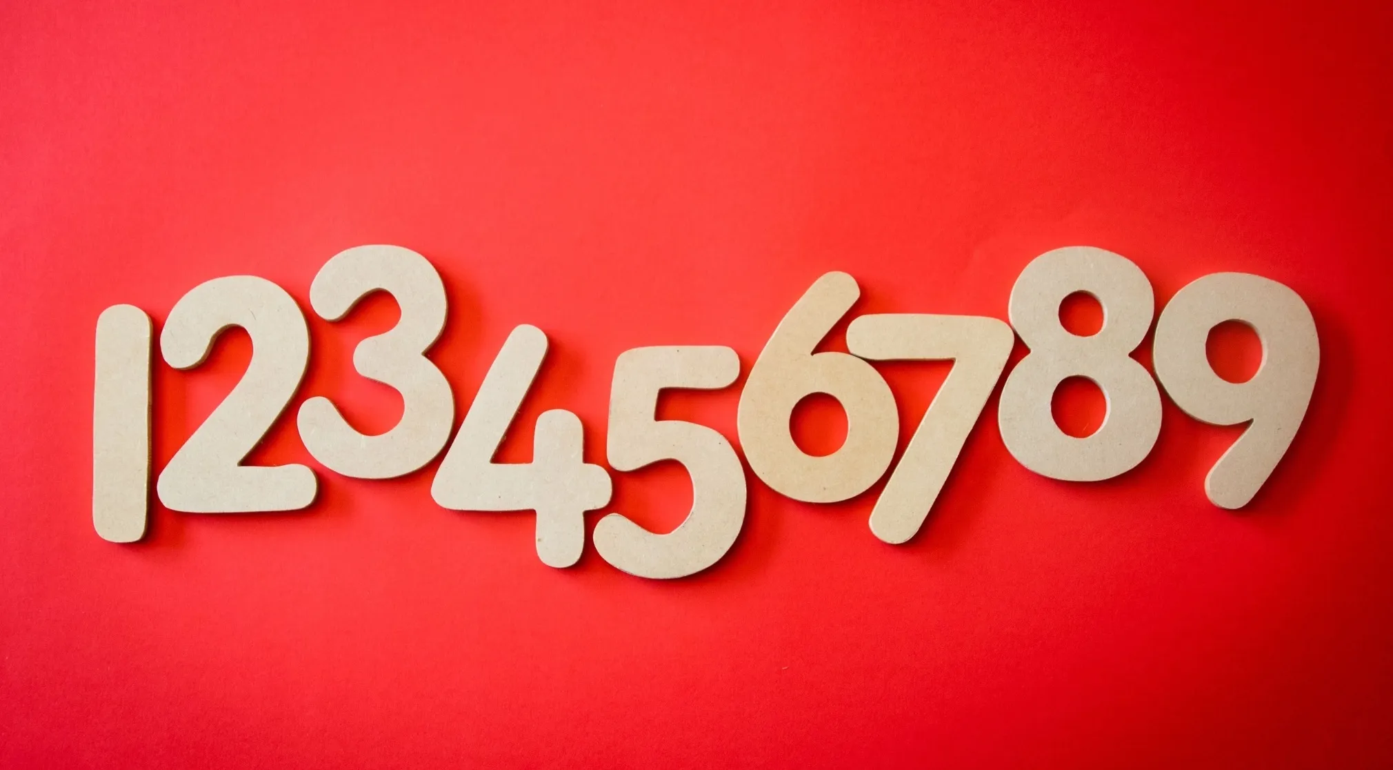 Wooden numbers 1 through 9 on a red background. Chinese exam math for the sum of the first 10 natural numbers.
