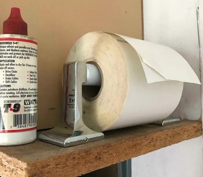 A roll of paper in a holder next to a bottle of cleaning solution. Creativity turned old junk into something worth keeping.