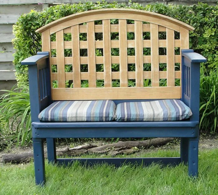 Blue outdoor bench with striped cushions, demonstrating creativity turning old junk into something worth keeping.