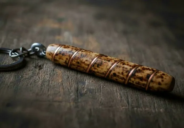 A handmade wooden keychain with copper accents, showing how creativity turns old junk into something new.