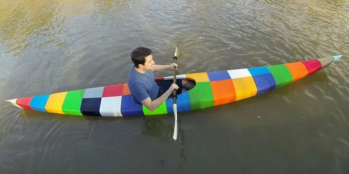 A person paddles a colorful, block-patterned 3D printing kayak on the water, highlighting amazing 3D printing creations.