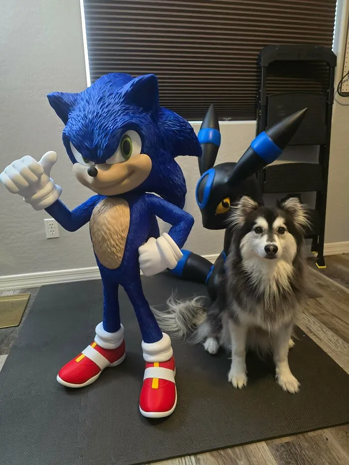 A loyal dog sits beside two amazing 3D printing creations: a large Sonic the Hedgehog and a dark Pokemon character.
