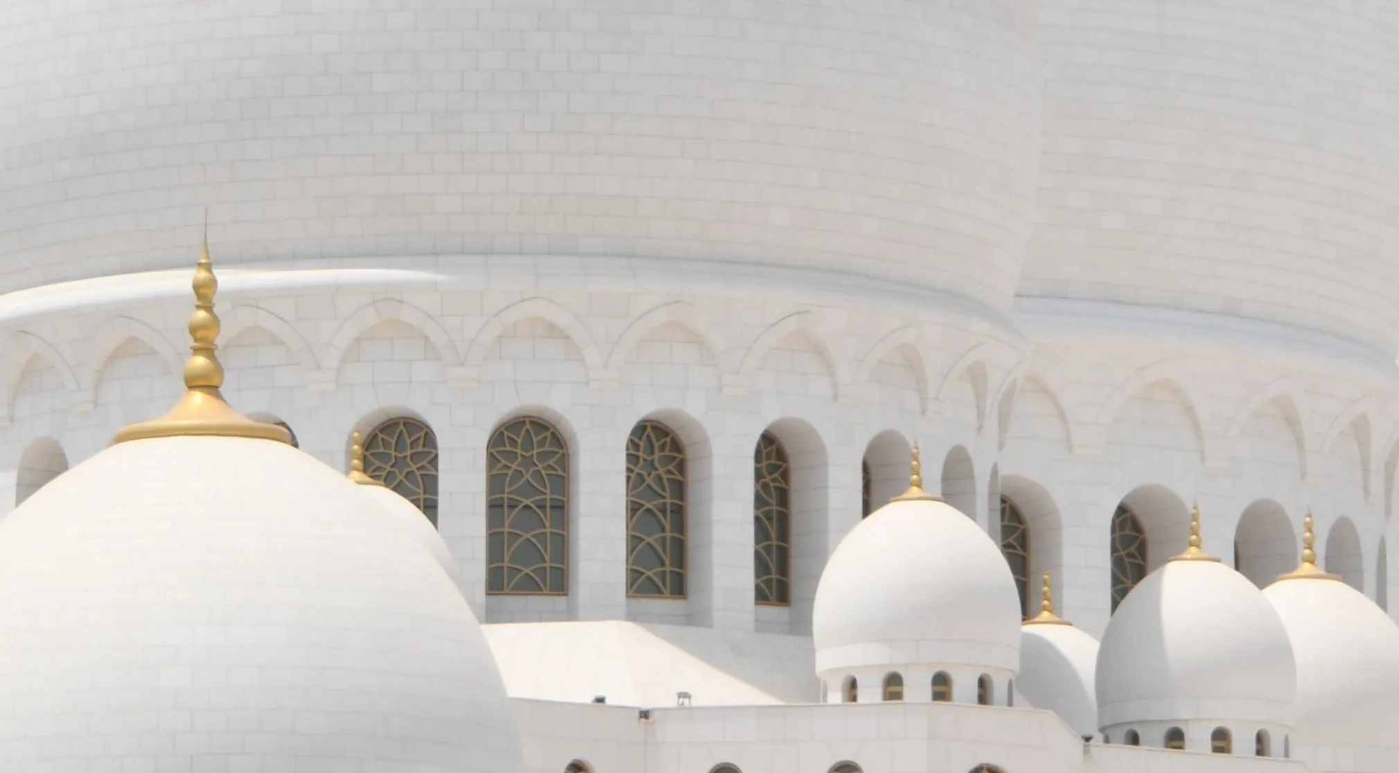 A close-up of a white marble landmark featuring multiple domes with golden spires and arched windows. Zoomed in landmark.