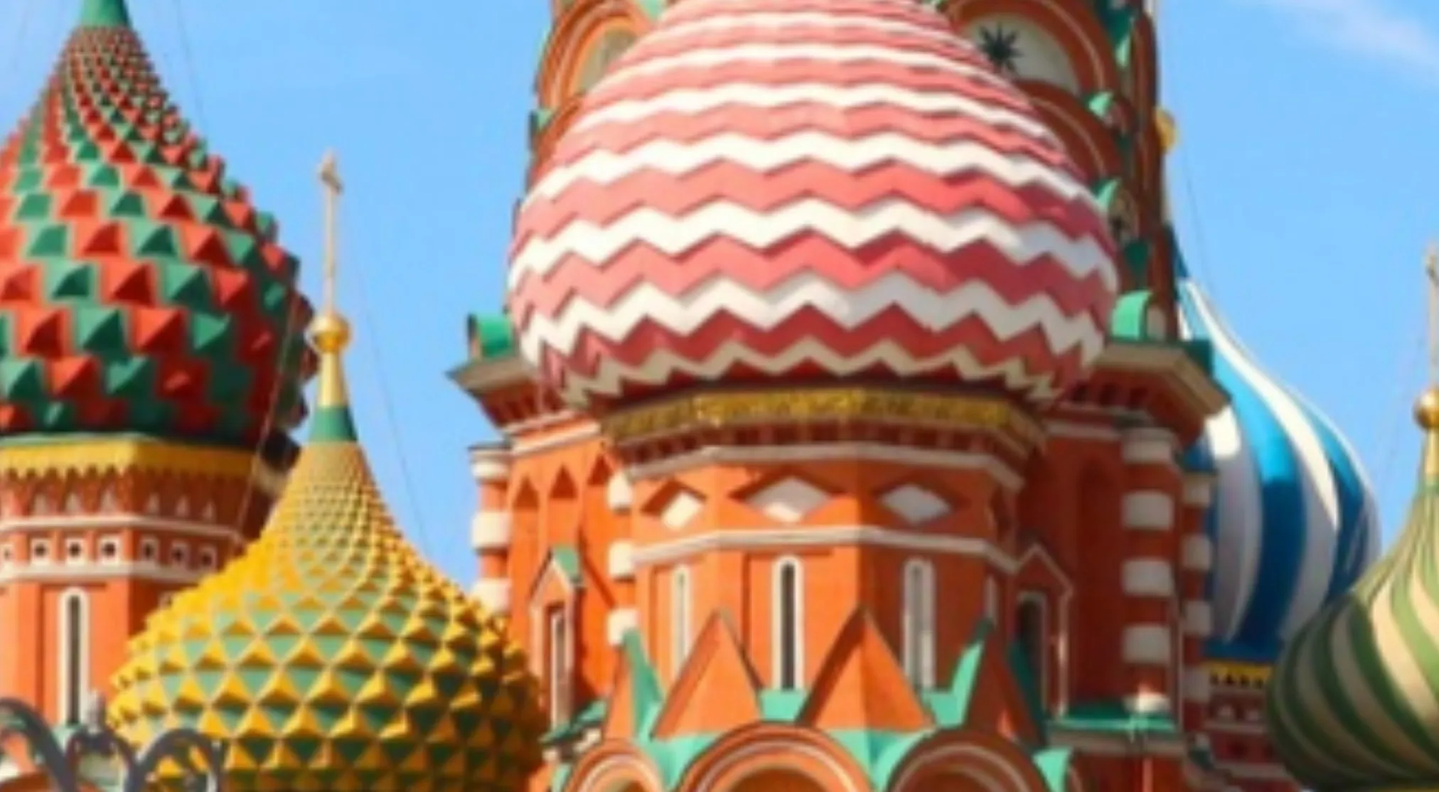 A zoomed-in image of colorful, patterned domes with various textures, a famous landmark against a blue sky.
