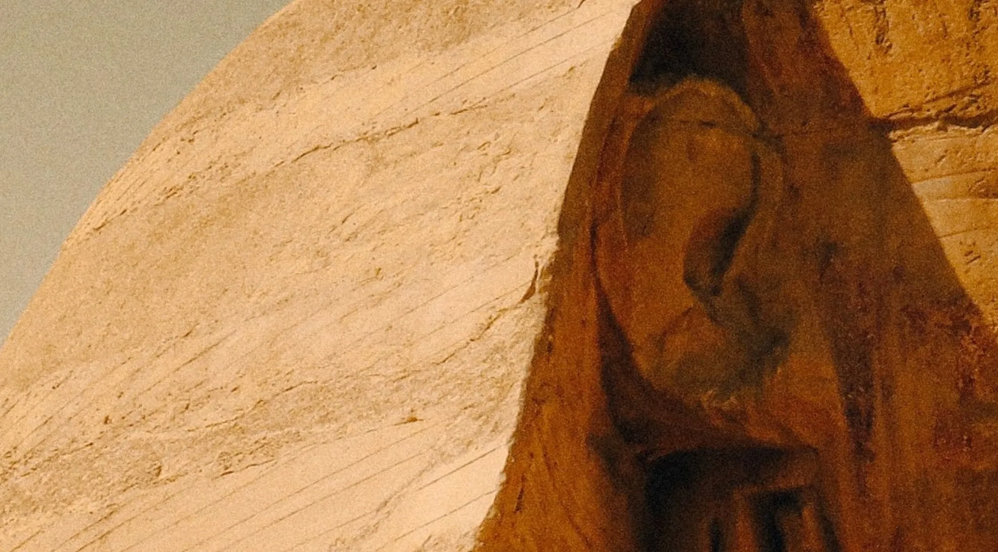 Zoomed in landmarks: a close-up of light brown weathered stone with a darker, shadowed alcove revealing a sculpted figure.