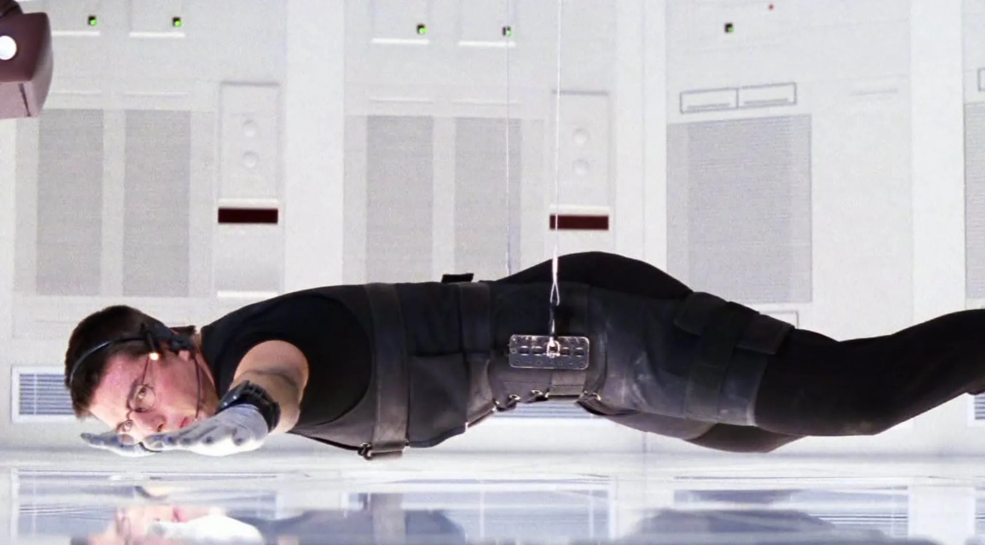 Tom Cruise as Ethan Hunt in a classic Mission: Impossible film scene, suspended horizontally.
