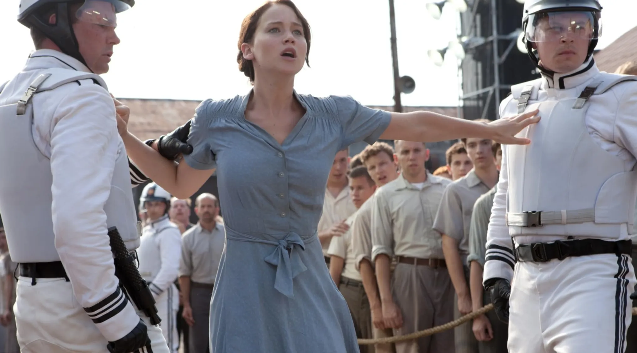Jennifer Lawrence as Katniss Everdeen, held by guards, in The Hunger Games movie franchises.