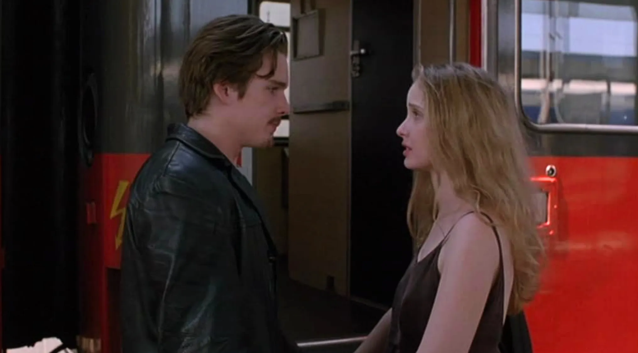 Celine and Jesse from The Before Trilogy movie franchises stand facing each other on a train platform.