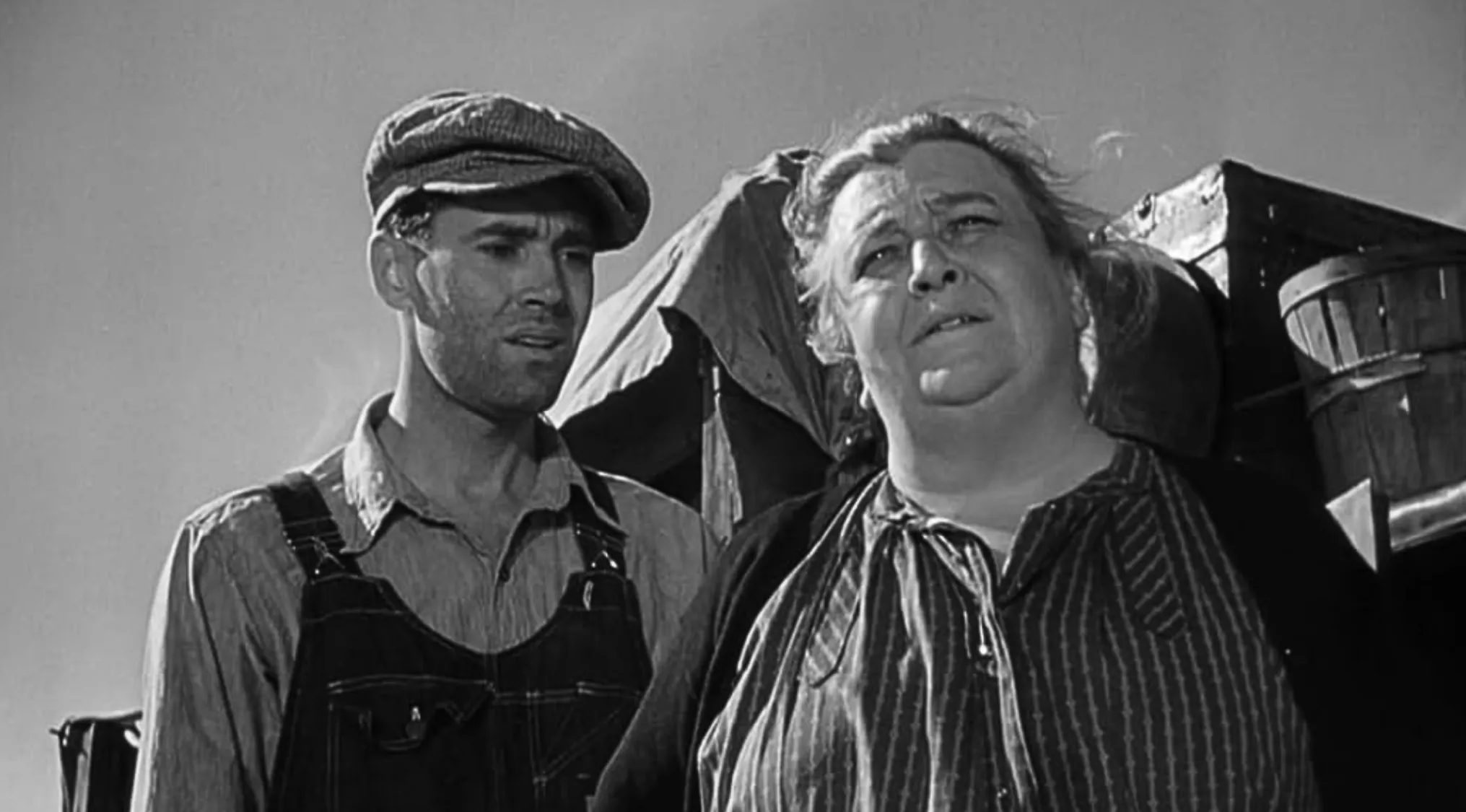 A black and white still image showing two characters from The Grapes of Wrath, a man and an older woman. The family in The Grapes of Wrath.