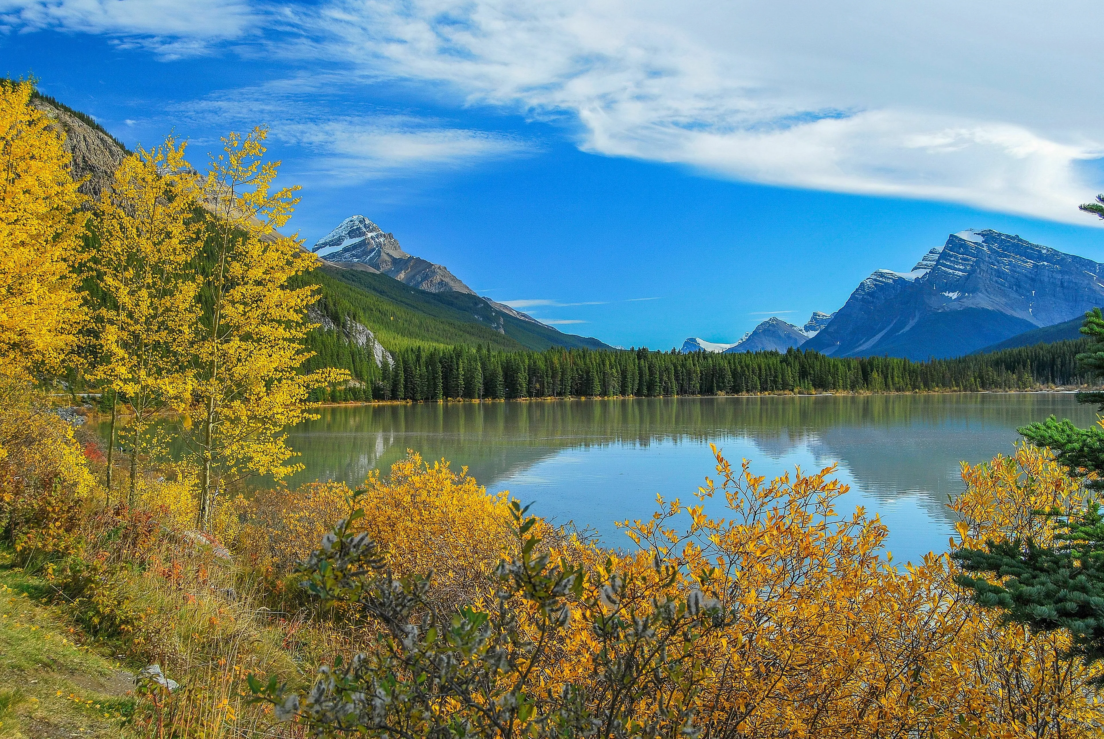 A serene landscape of natural lakes surrounded by forests and mountains under a blue sky.