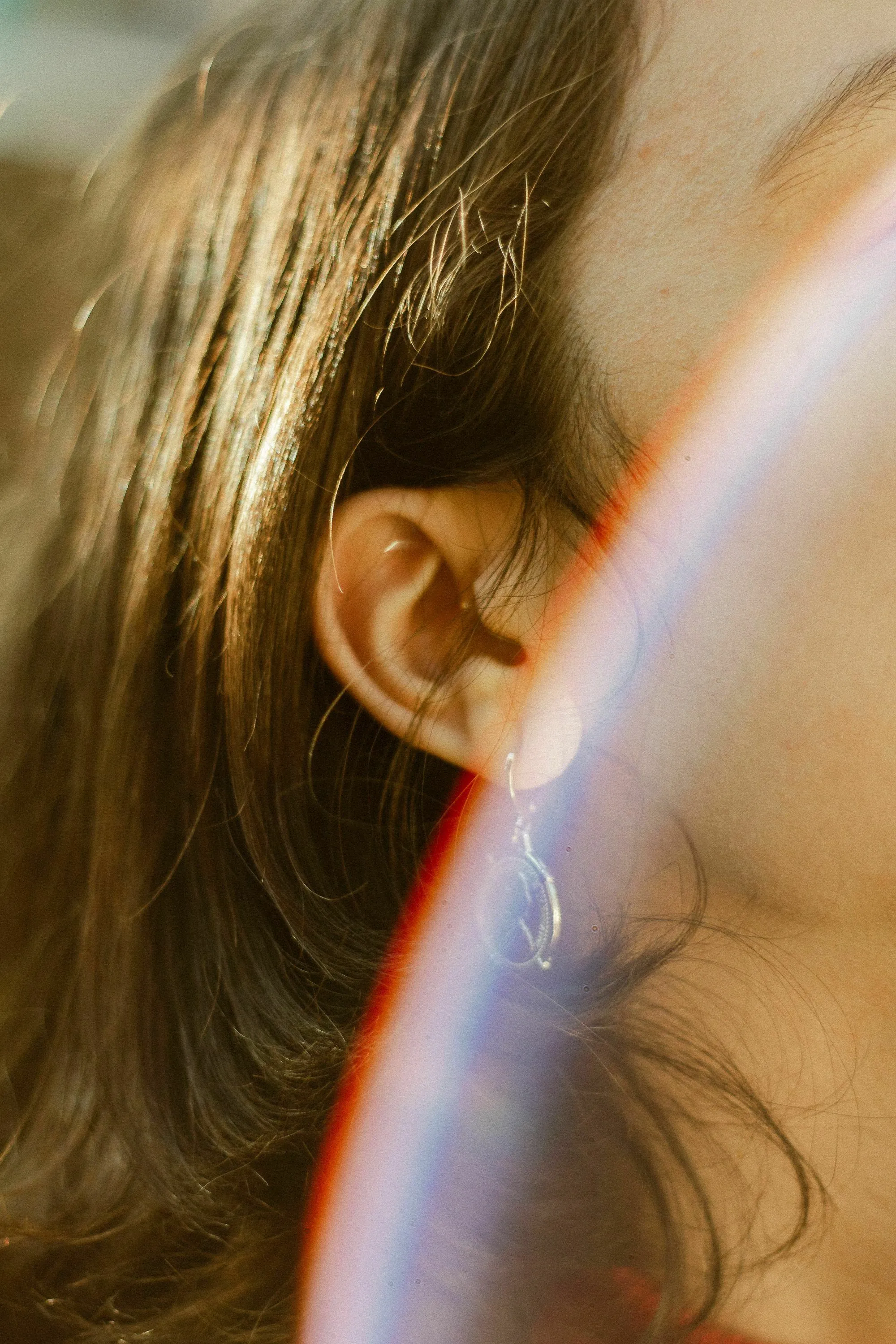 Close-up of a human inner ear with long hair, highlighting its role in hearing and body balance.