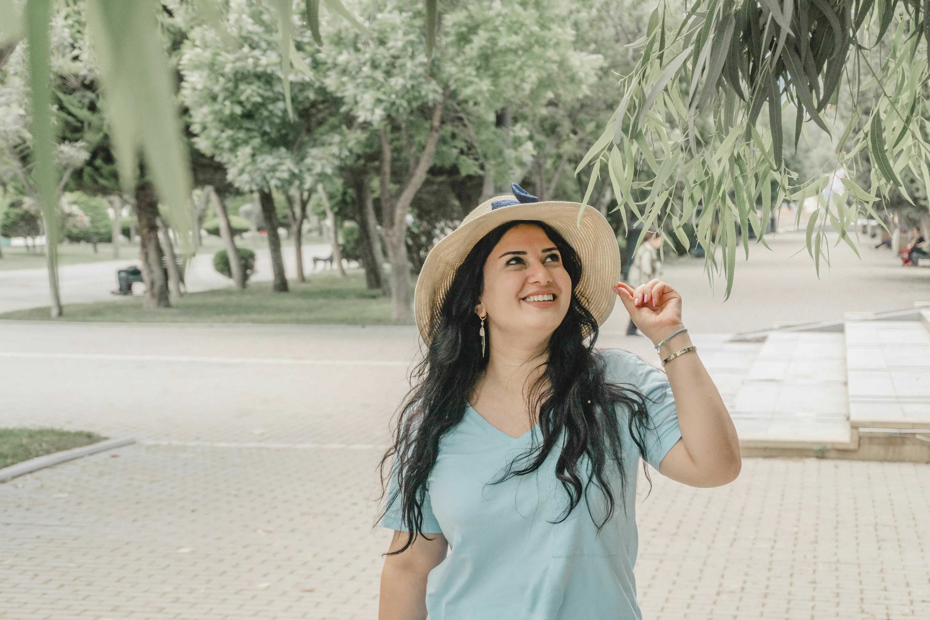 A woman in a straw hat smiles while walking outside, enjoying her ideal vacation.