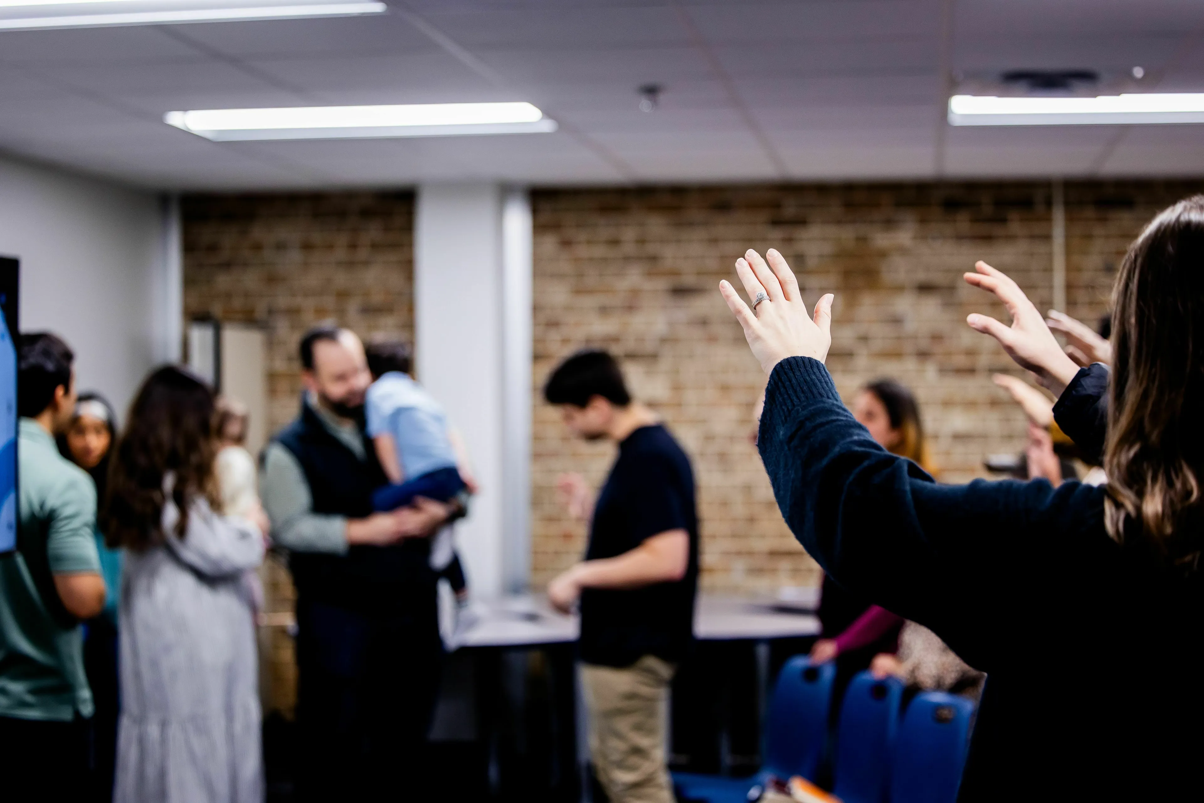 People interacting in a room, with one person raising their hands. The scene relates to how one would leave a conversation.