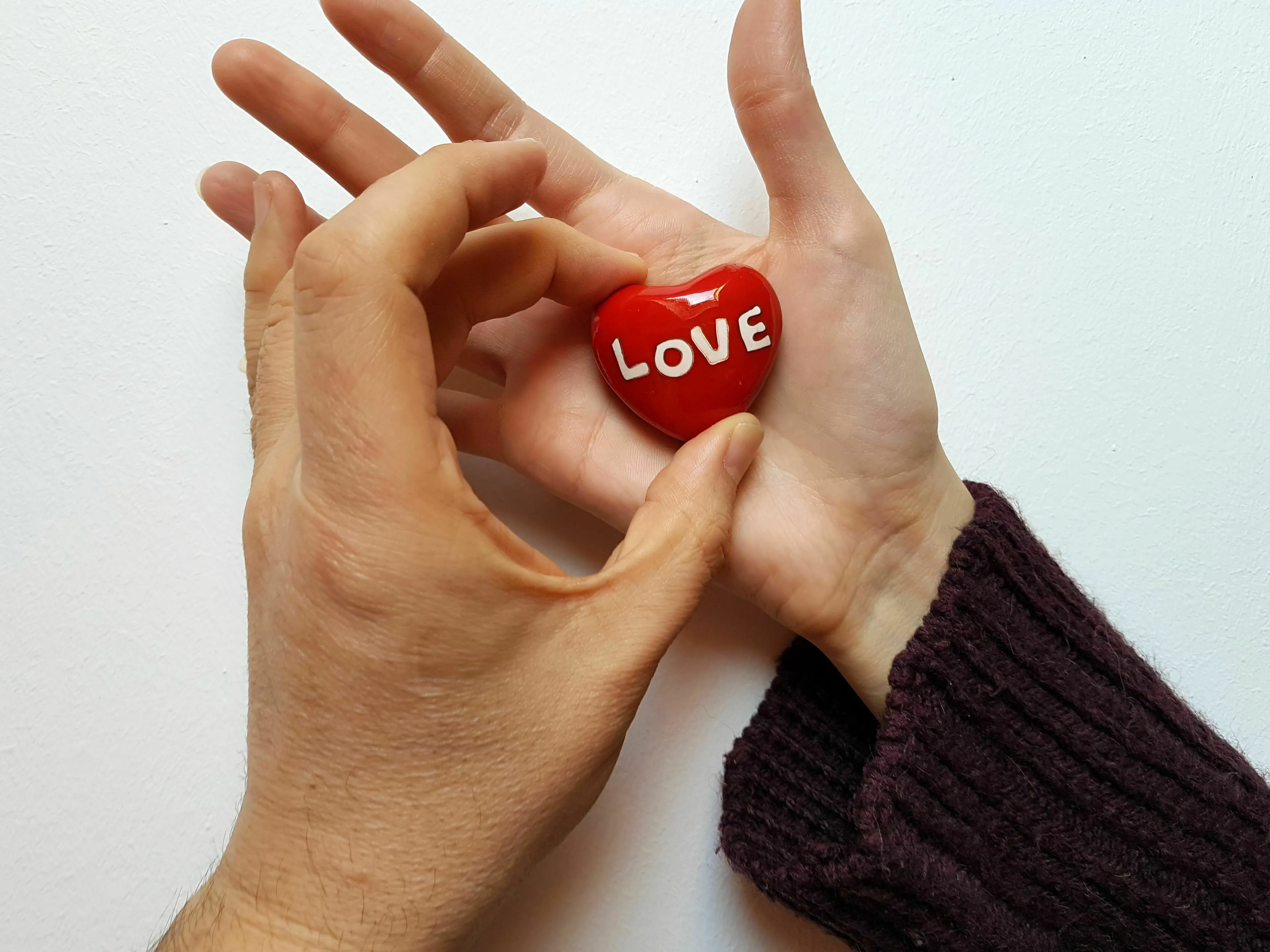 Two hands holding a red heart with the word LOVE, symbolizing the reason people love a meal.