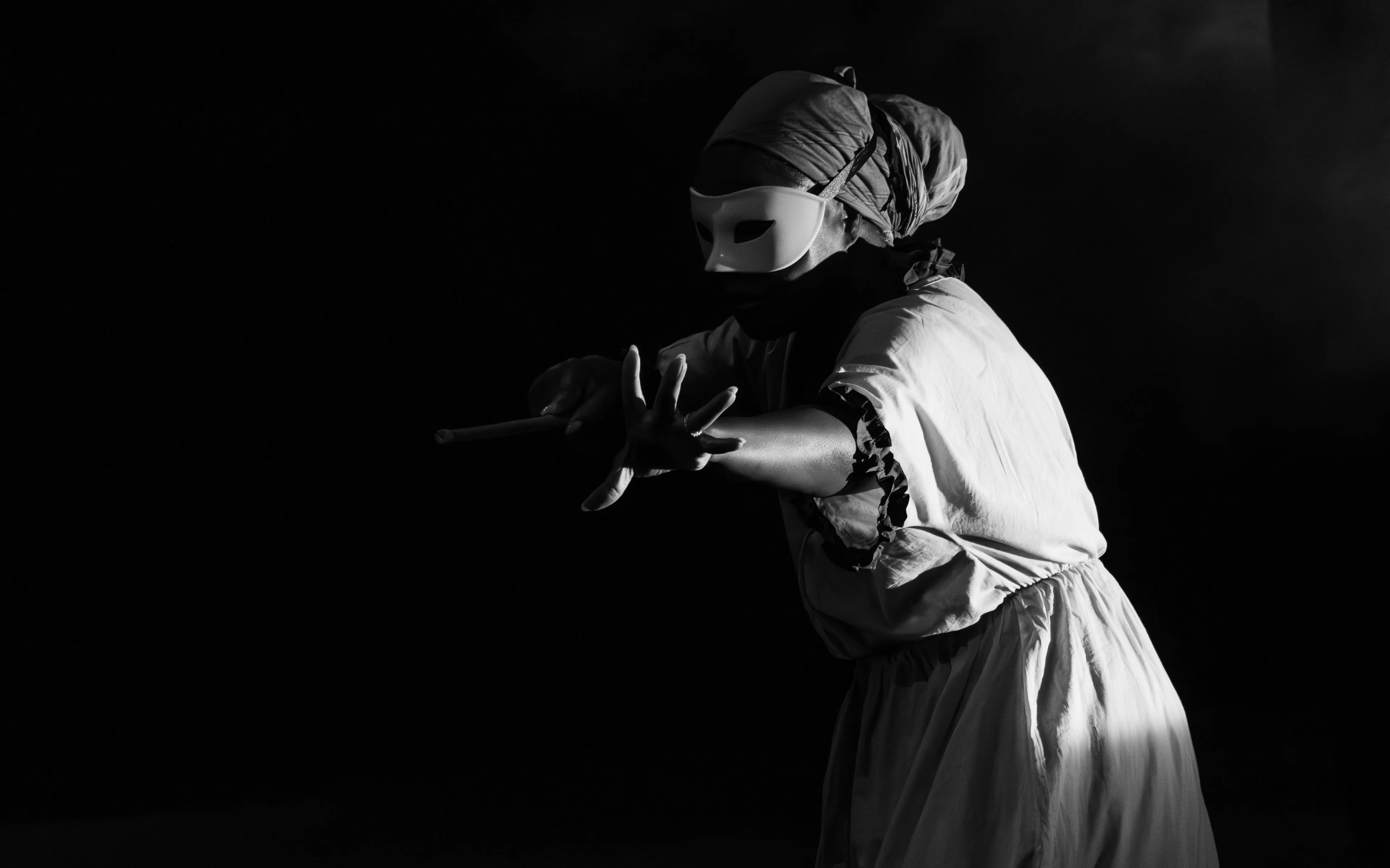 A person in a mask and flowing clothes extends a hand in the dark, embodying a movie villain's line delivery.