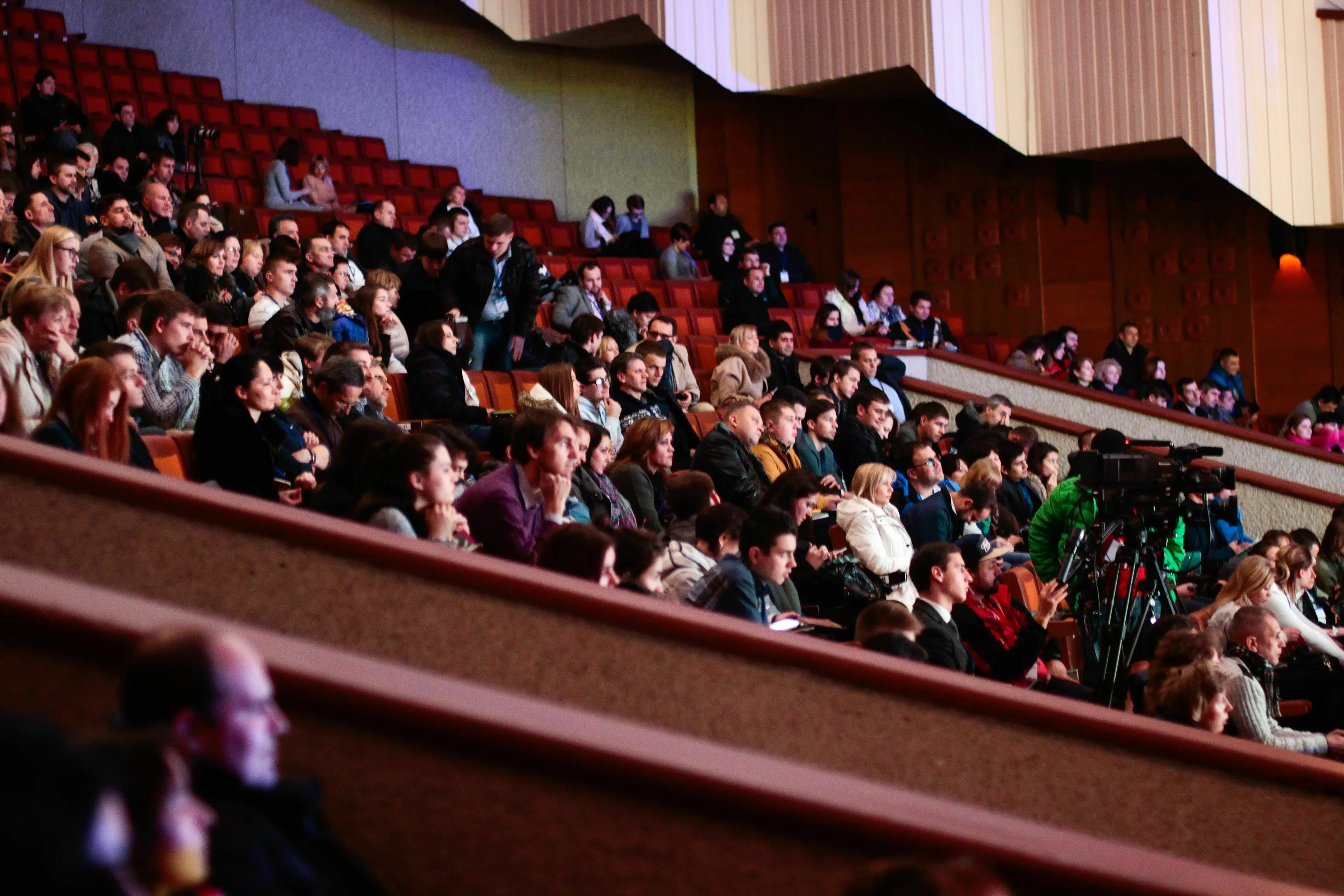Audience in a large theater watching a performance, experiencing feelings about a movie villain.