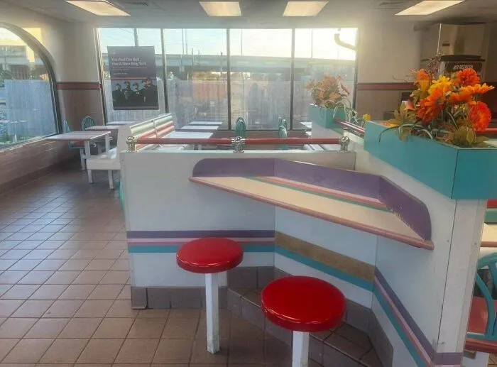A bright fast-food restaurant interior with retro decor, including red stools, reflecting life in the 90s.