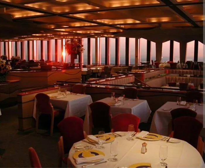An elegant restaurant interior with a sunset view, reminiscent of dining experiences from life in the 90s.