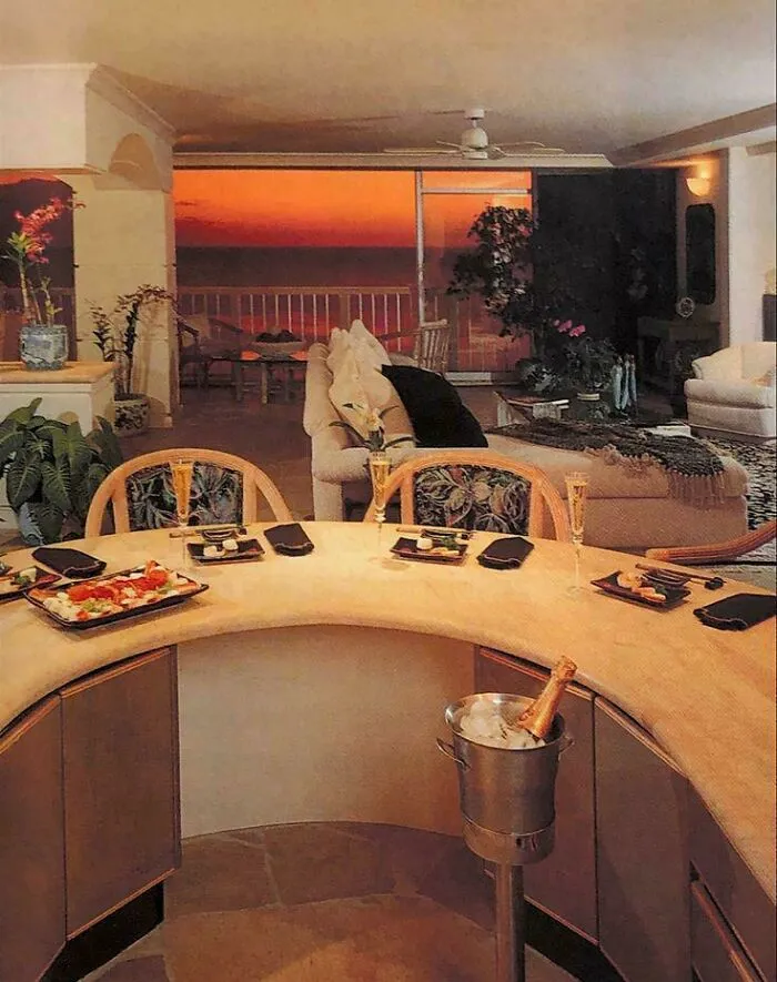 A luxurious 90s living room with a curved bar and ocean view at sunset, defining life in the 90s.