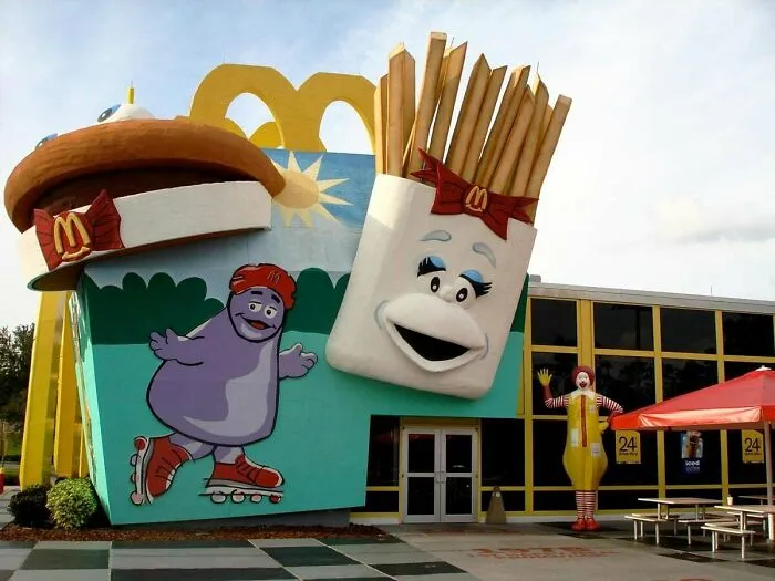 An extravagant 90s McDonald's building with giant hamburger and french fry mascots, and Ronald McDonald.