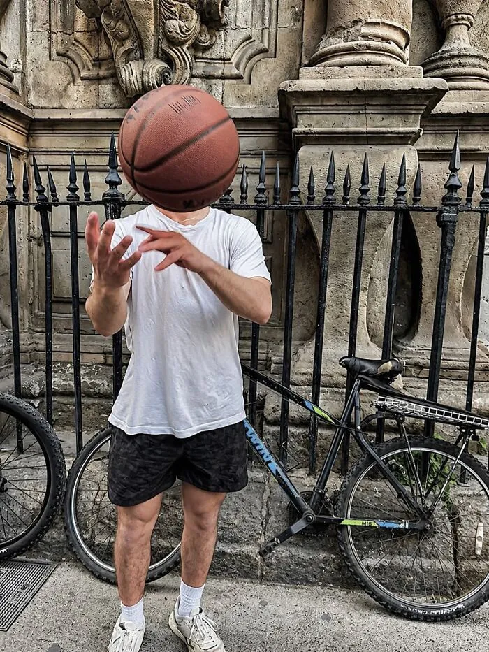 Fotos accidentales: hombre con una pelota de baloncesto en la cabeza, junto a una bicicleta, capturado en el momento justo.