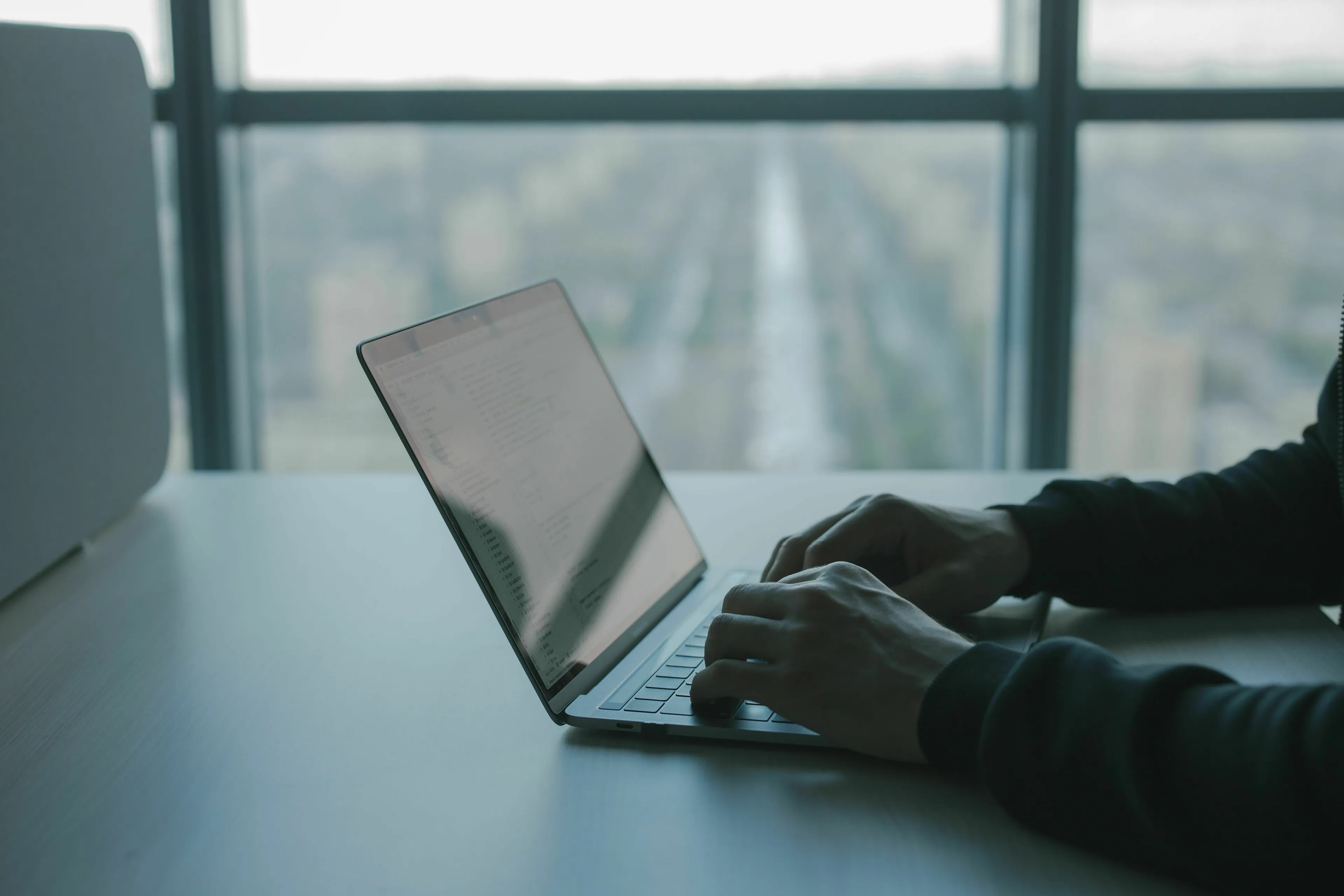 Person typing on laptop, receiving urgent emails, revealing their stress response.