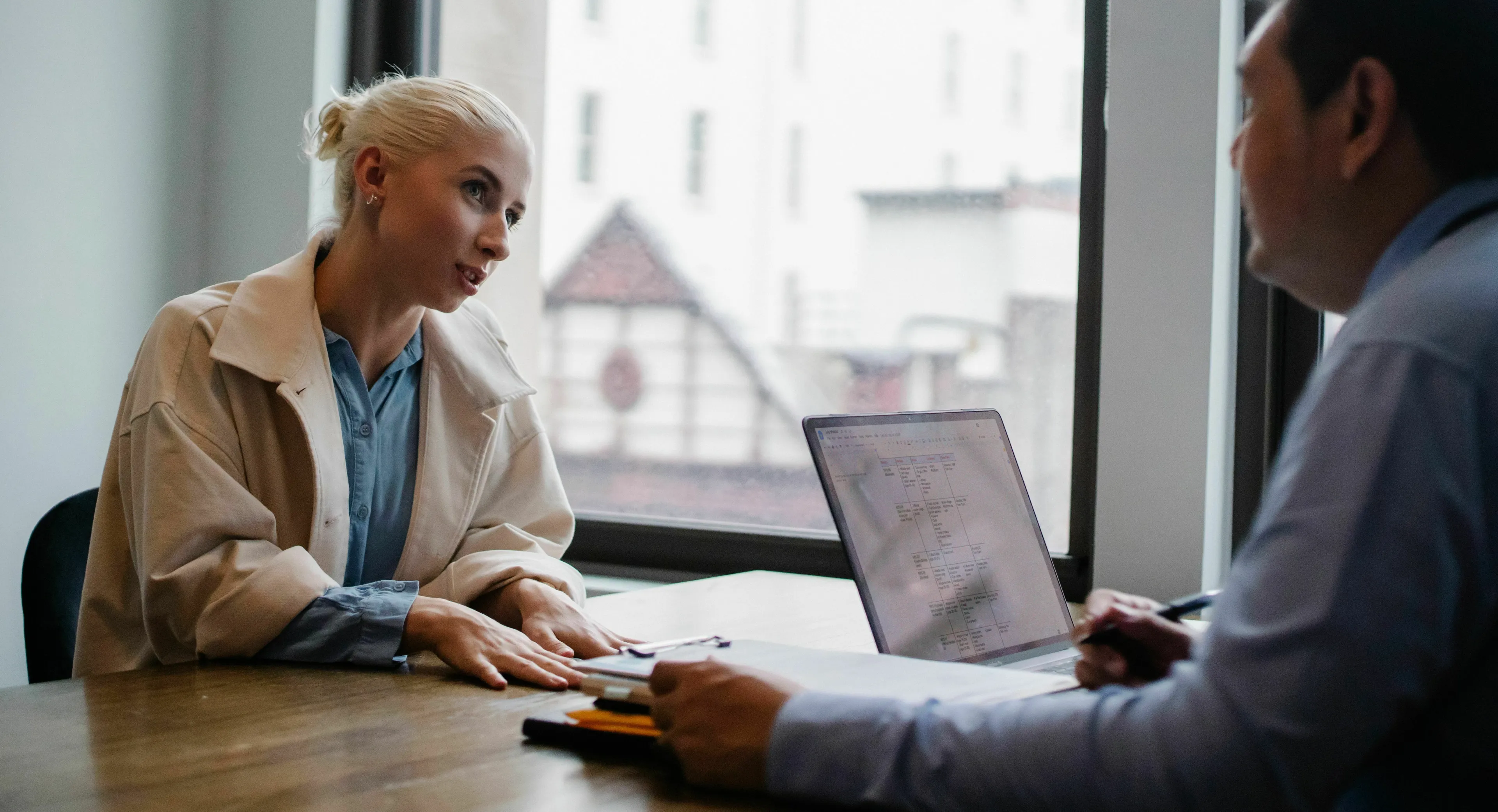 Two people at a desk, one receiving criticism about work in a meeting, revealing her stress response.